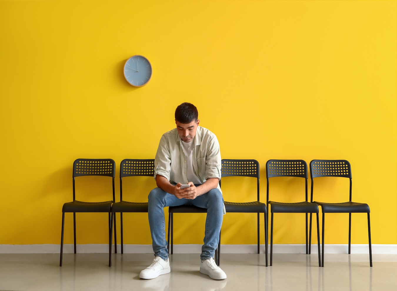 A lone man sits in a waiting room, symbolizing the dwindling candidate pools and the challenges businesses face in attracting qualified job applicants.