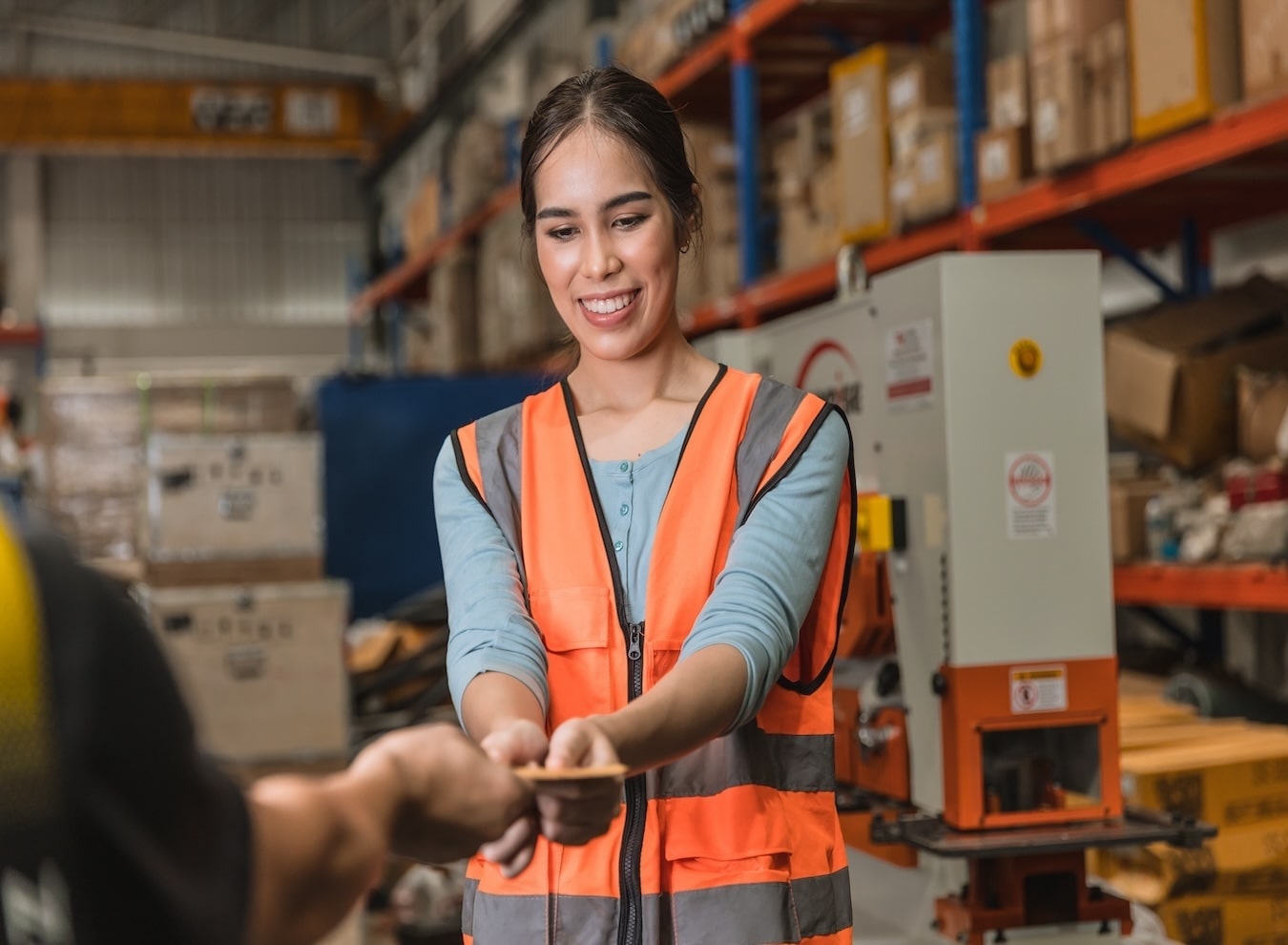 A woman working an industrial job in a warehouse is being handed cash, symbolizing payment for her labor in a manual workforce setting.